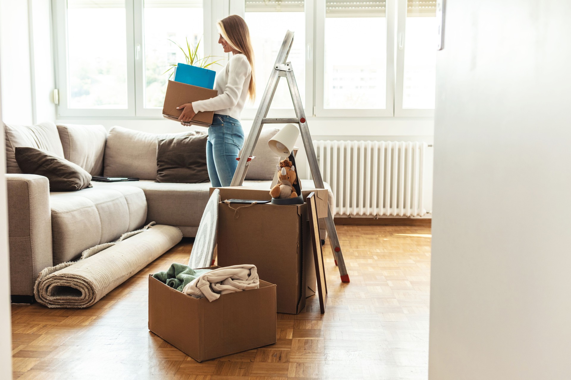 Shot of a woman carrying boxes into her new place. Young woman holding cardboard box. Moving into new home.